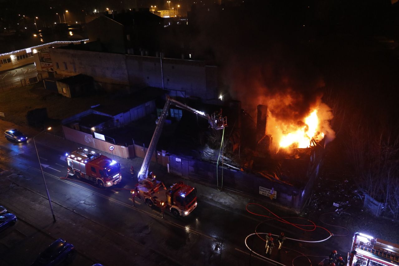 Über Uns Firemen battling an intense urban building fire at night with fire trucks on the scene.